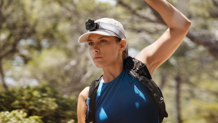 woman stretching before doing exercise in the wilderness, equipped with Insta360 GO Ultra clipped to her hat, using Magnetic Easy Clip
