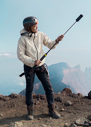 A man climbs a mountain using Insta360 X4 on an Extended Selfie Stick.