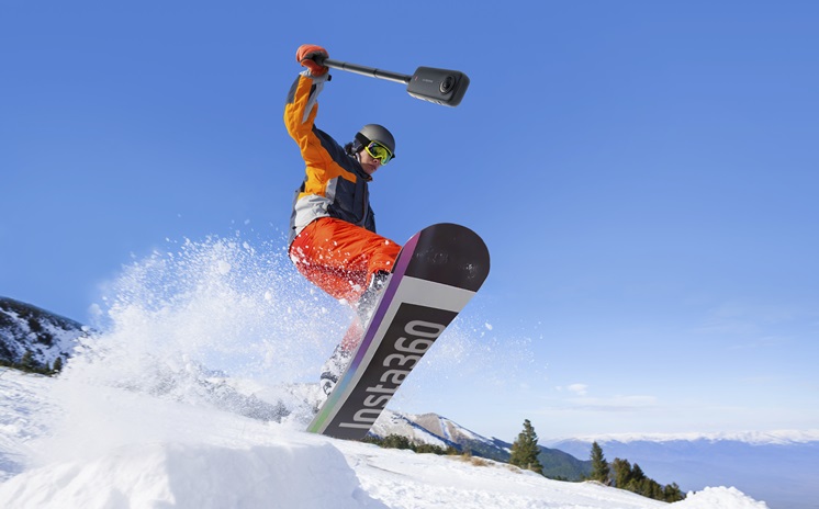 A man is skiing holding an camera.