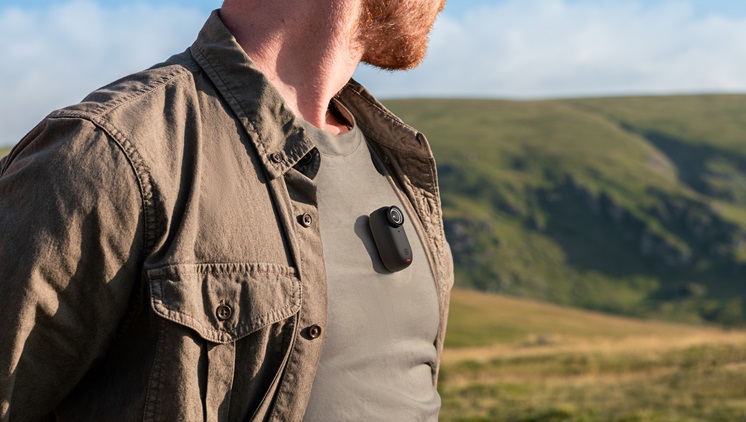 This is a photo of a man with a tiny black camera held on his chest.