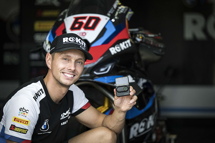 A rider posers with Insta360 GO 3S in front of a BMW ROKit World Superbike.