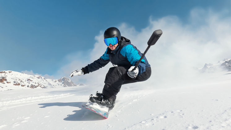 snowboarder holding Insta360 X5 camera while snowboarding