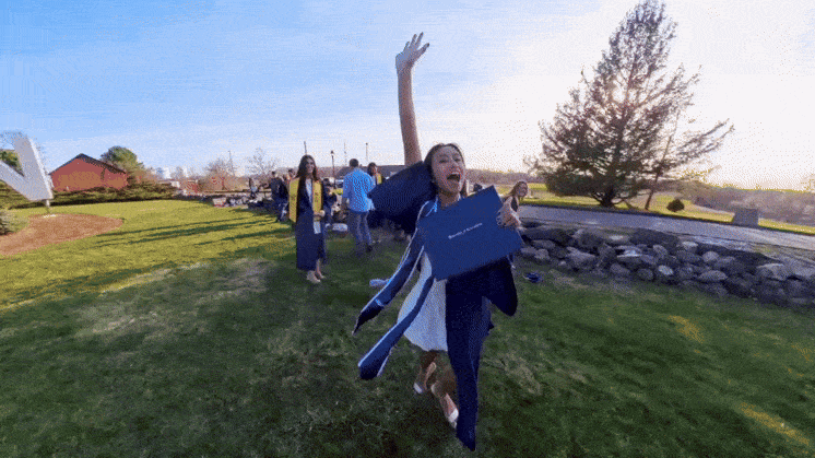Students spinning around or jumping while holding their diploma.