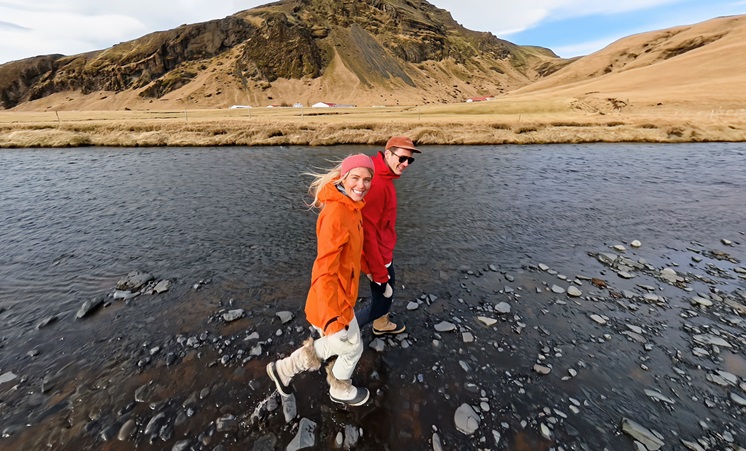 Two people walking along a river in Iceland