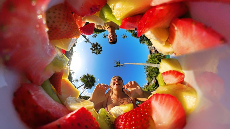 This is an angle form a fruit bowl that two people sit in front of it.