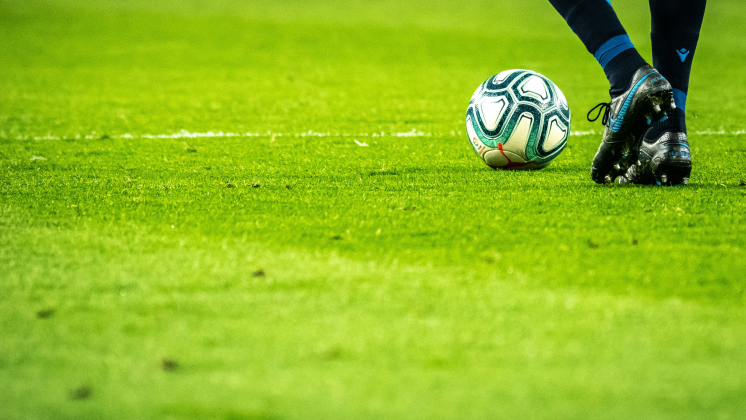 Low angle shot of a player with the ball at their feet on a grash pitch