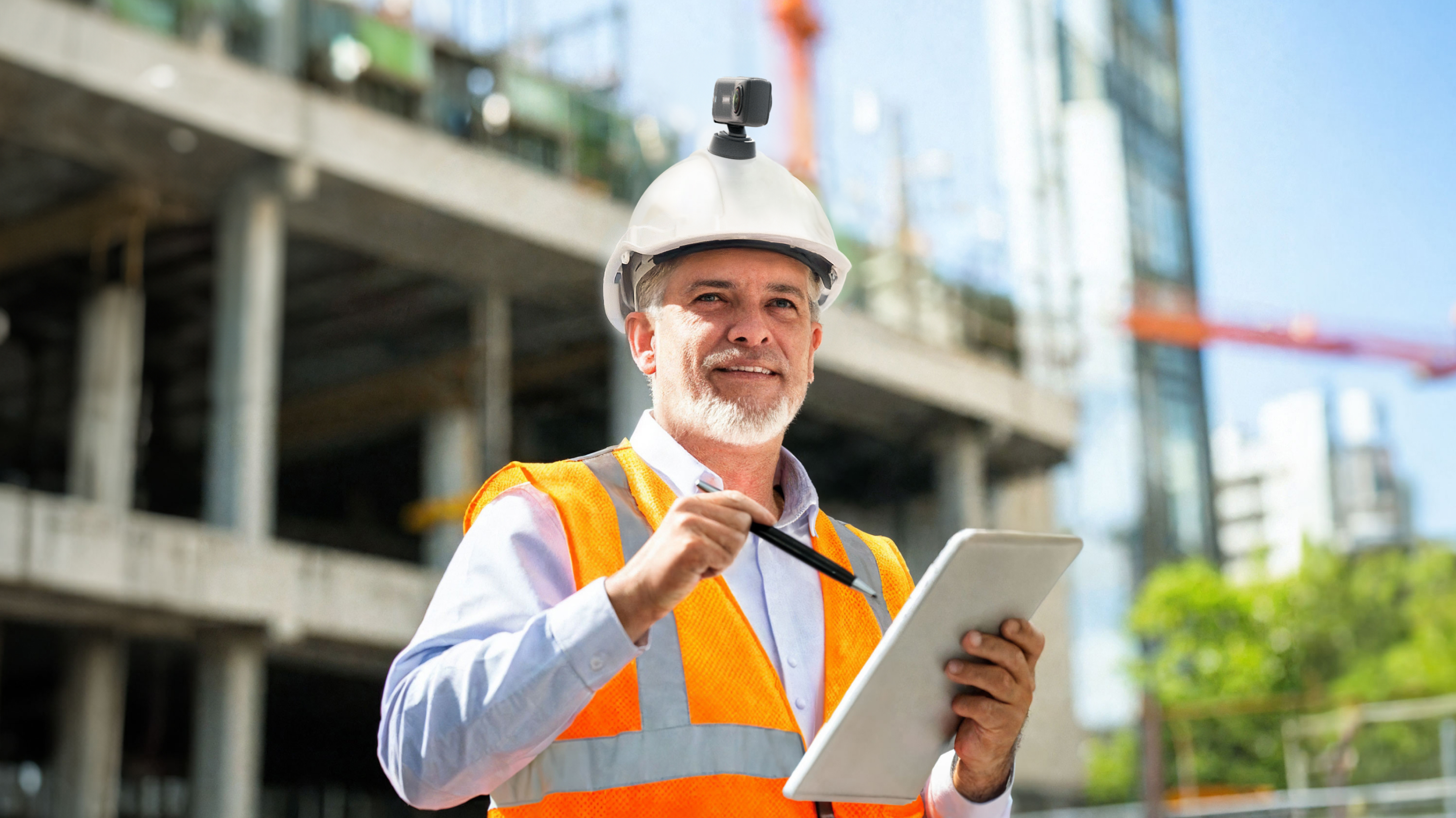 A construction site worker in an orange high-vis with Insta360 X4 mounted onto his hard hat.