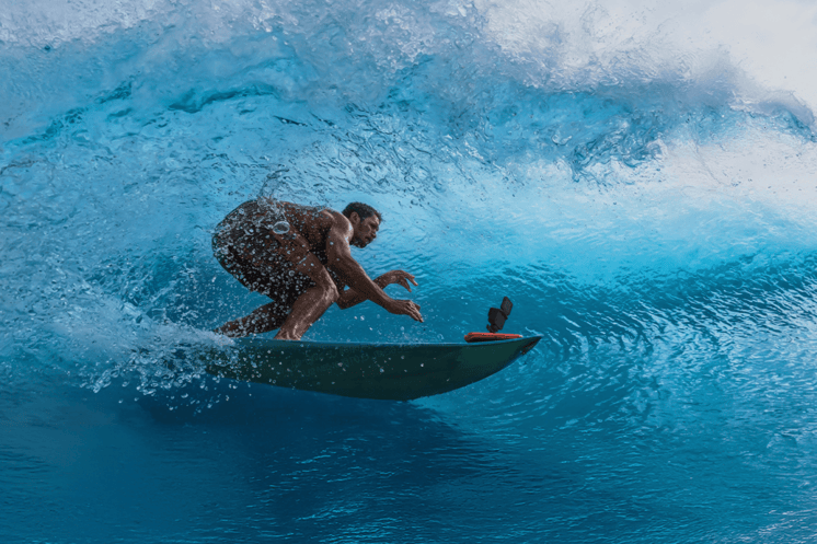 A surfer using an Insta360 Ace Pro 2 to film himself as he passes under a large wave.