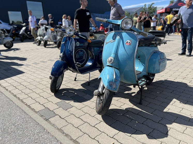 Two classic scooters next to each other at an exhibition.