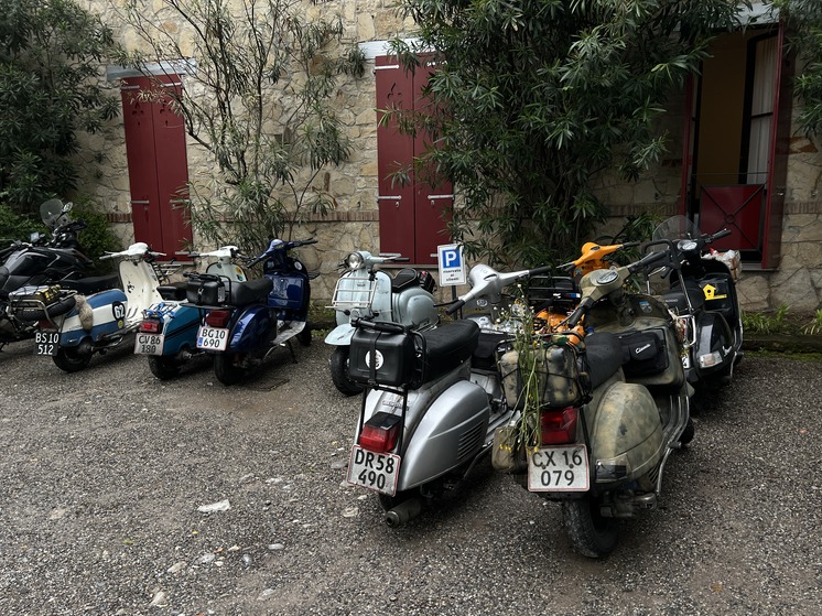 A line of classic scooters parked outside a hotel.