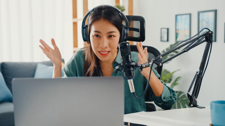 Recording a podcast on her laptop computer with headphones and microphone.