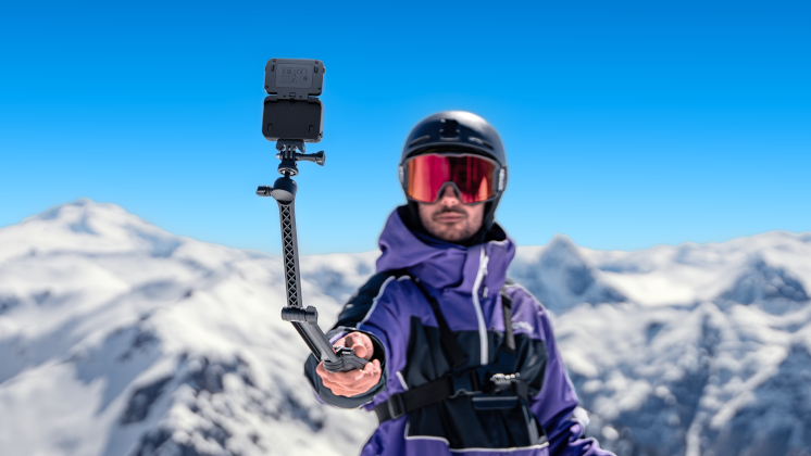 A skier using Insta360 Ace Pro as a ski camera on the Multi Mount with some mountains in the background.