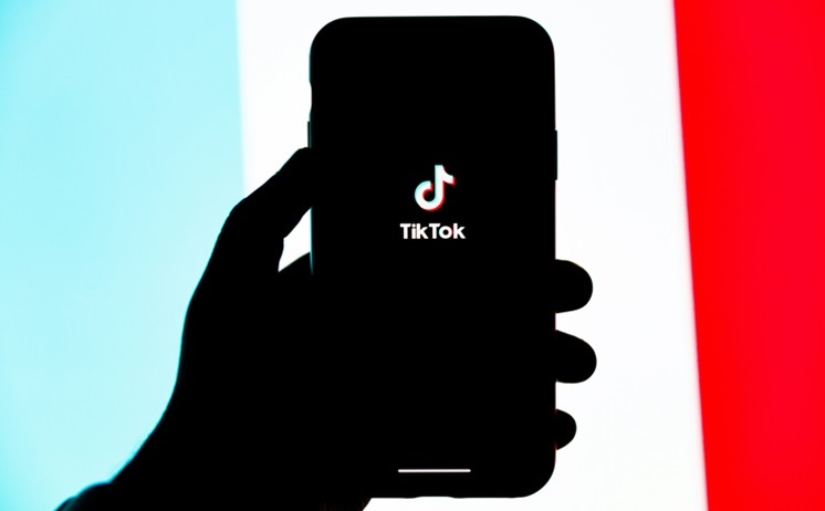 This is one hand holding a phone showing the TikTok logo