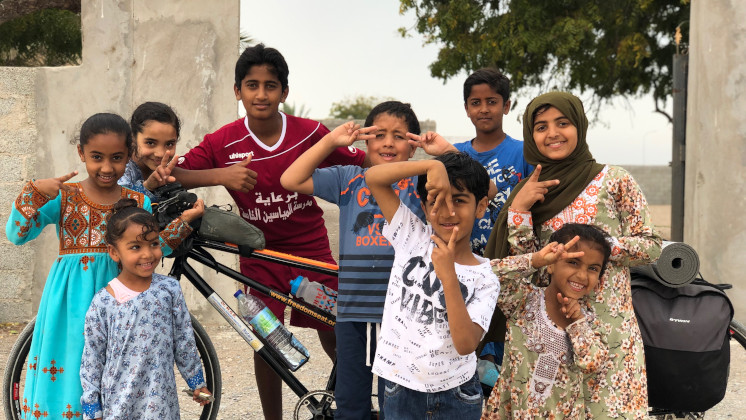 A group of children around Kumar's tandem bike.