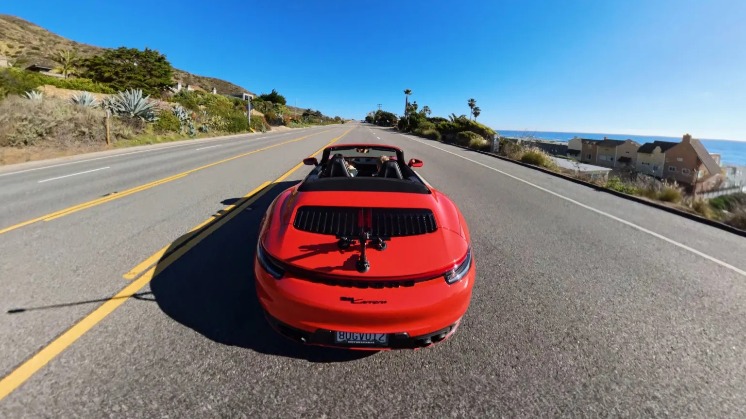 An image of a red car from behind driving down a road.