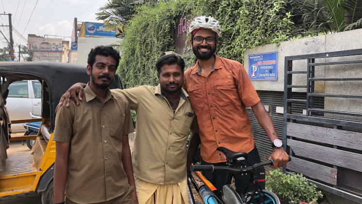 Kumar with two men standing next to his tandem bike.