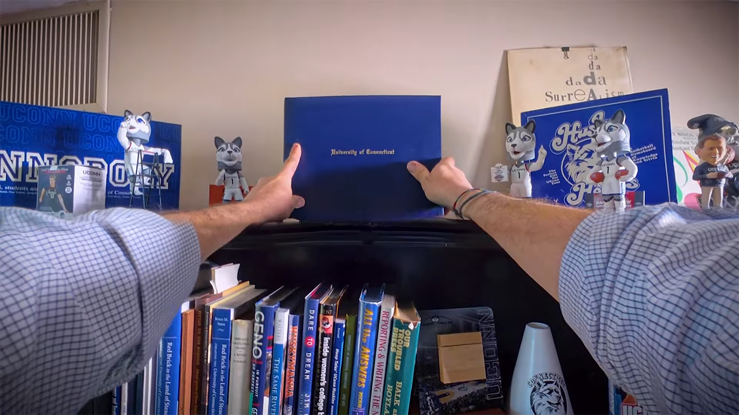 A POV of someone putting their diploma from UConn on a shelf.