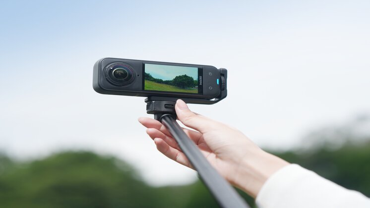Insta360 X5 mounted horizontally on a selfie stick.